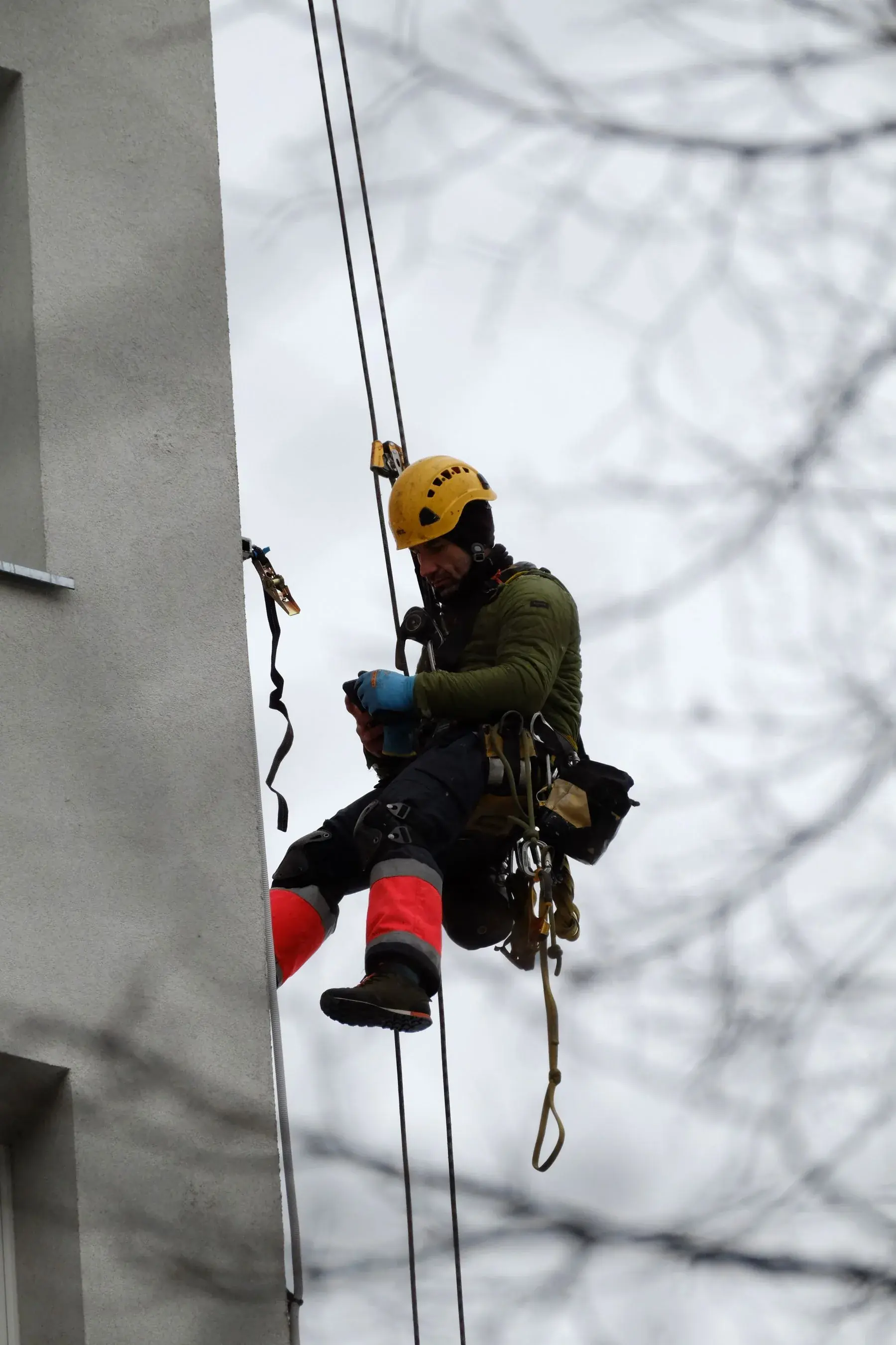 Técnico de acesso por corda com equipamento de segurança em detalhe