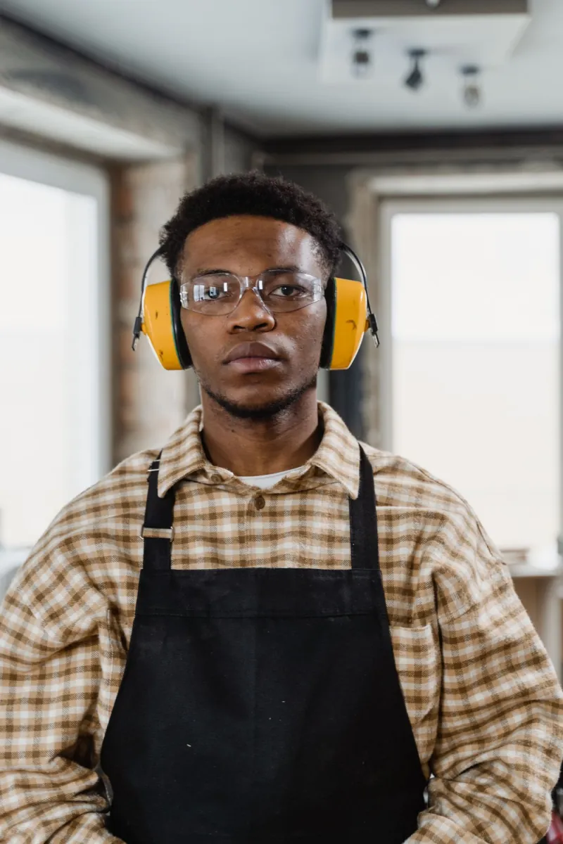 Trabalhador usando abafador auricular e óculos de proteção em oficina